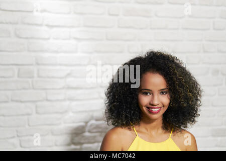 Portrait of happy African American Woman smiling contre mur blanc comme arrière-plan, copy space Banque D'Images