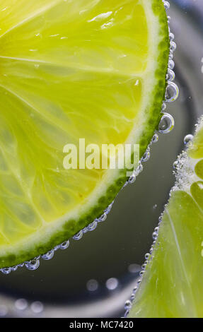 Tranches de Lime Macro dans l'eau pétillante avec bulles Banque D'Images