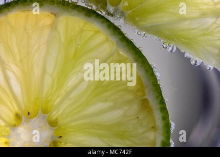 Tranches de Lime Macro dans l'eau pétillante avec bulles Banque D'Images