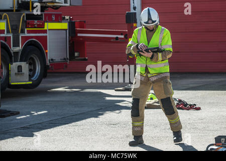 Seule l'aide de tablette ordinateur pompier au travail à l'extérieur à côté de fire engine Banque D'Images