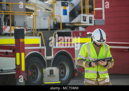 Seule l'aide de tablette ordinateur pompier au travail à l'extérieur à côté de fire engine Banque D'Images