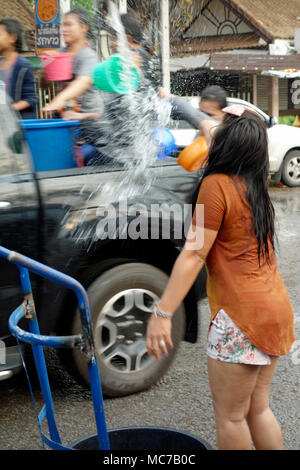 Songkran 2018, Nouvel An thaï, jeune femme thaïlandaise jetant de l'eau plus de passagers passant par en camionnette sur la route entourant Nong Prajak Park, Udon Thani, l'Isaan, Thaïlande Banque D'Images