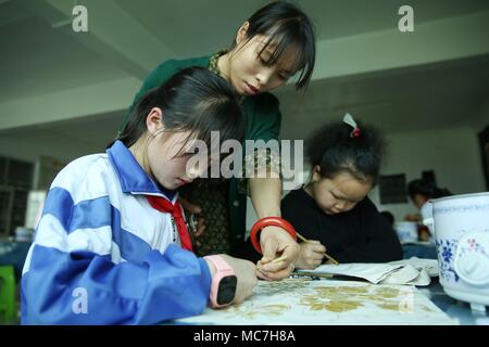 Danzhai, province du Guizhou en Chine. 13 avr, 2018. A l'enseignant guide les élèves dans l'élaboration d'images batik à Chengguan n° 1 l'école primaire de Danzhai County, au sud-ouest de la province du Guizhou, en Chine, le 13 avril 2018. Les classes sont d'intérêt destiné à enrichir la vie scolaire des élèves ici. Credit : Huang Xiaohai/Xinhua/Alamy Live News Banque D'Images