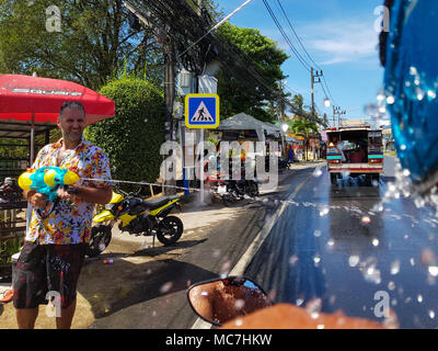 Phuket, Thaïlande - 13 Avril 2018 : l'homme de verser de l'eau de l'arme sur moto conducteur célébrer le Nouvel An traditionnel thaïlandais - Songkran Festival. Crédit : Anna Moskvina/Alamy Live News Banque D'Images