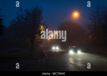 Véhicules voyageant le long d'une route de banlieue la nuit en Angleterre. Banque D'Images