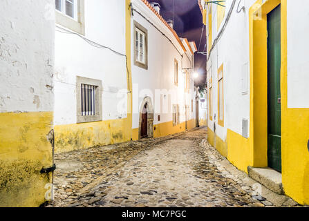 Rue étroite avec des maisons blanches et jaunes par nuit à Evora (Alentejo, Portugal Banque D'Images