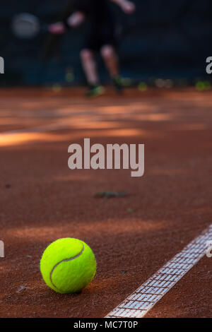 Libre de balle de tennis sur un terrain avec une personne floue en arrière-plan Banque D'Images