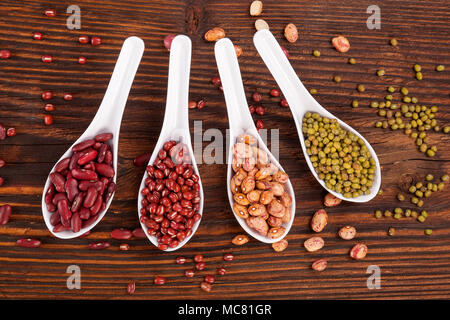 Diverses légumineuses en bonne santé dans les cuillères en bois sur table à partir de ci-dessus. Les haricots mungo. L'alimentation saine. Banque D'Images