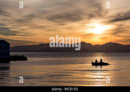 Silhouettes de deux hommes l'aviron dans un petit bateau de pêche à un lever du soleil d'or à Corfou, Grèce. Image horizontale Banque D'Images