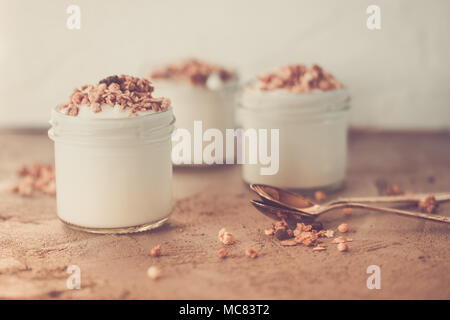 Yaourt au muesli fait d'avoine, raisins secs, riz soufflé, de chocolat et de bananes séchées. Petit-déjeuner sain pour la famille. Alimentaire sain. Banque D'Images