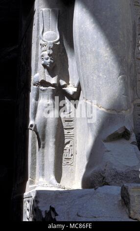 La déesse Isis sous les jambes de géant de Ramsès II, dans le temple de Louxor, Egypte mythologie égyptienne, la déesse Hathor, avec le solaire-lunaire : Harnais de secours de granit dans le cadre de la gigantesque statue de Ramsès II. Dans la salle hypostyle du temple de Louxor Banque D'Images