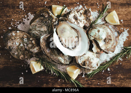 Oyster shell ouvert avec le citron et le sel sur une planche en bois Banque D'Images