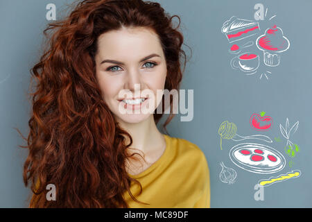 Jeune Cuisinier souriant en pensant à la cuisson des aliments savoureux Banque D'Images