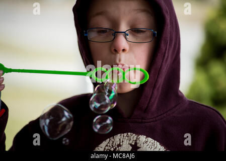 Un jeune garçon souffle bulles à l'appareil photo. Banque D'Images