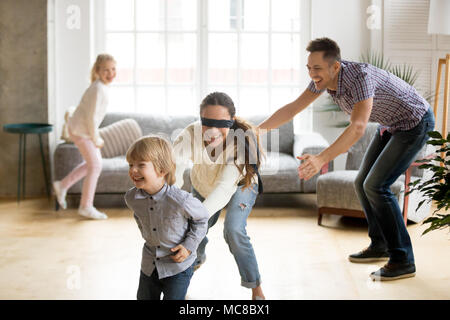 Les yeux bandés mère attraper petit fils joue à cache-cache à la maison, heureux les enfants s'amuser avec maman et papa, les parents avec les enfants passer du temps bien positionné en couverture Banque D'Images