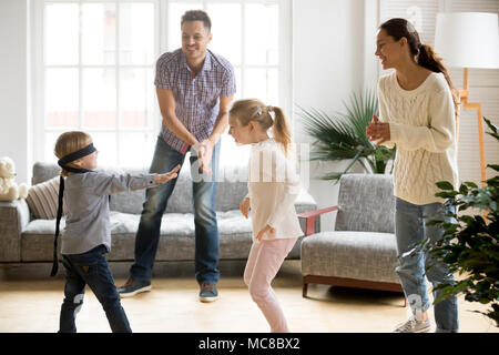 Les yeux bandés mignon petit garçon joue à cache-cache à la maison, les parents et enfants de passer du temps ensemble à rire profiter de jeu sur week-end, heureux de la famille Banque D'Images