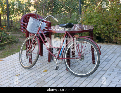 Meubles en plastique et old red bicyclette sur un patio Banque D'Images
