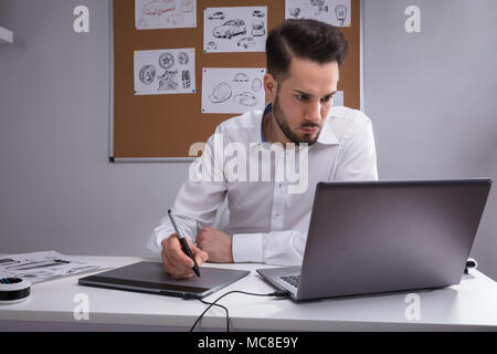 Concepteur de sexe masculin à l'aide de tablette graphique Working On Laptop Banque D'Images