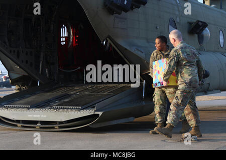 Le s.. L. Renee Lowery, le spécialiste des affaires religieuses pour la 35e Brigade d'artillerie de défense aérienne, face à la caméra et le major Benjamin Clark, 35e Brigade d'ADA, aumônier à l'opposé de l'appareil photo, chargez une boîte de dons de Girl Scout cookies sur un chinook à livrer aux soldats de la Force opérationnelle combinée Defender à Seongju, Corée du Sud, le 13 mars 2018. Les éclaireuses de Osan Osan Air Base recueillies et a donné près de 200 boîtes de biscuits à l'emplacement distant dans le cadre du projet du saumurage des cookies pour ceux qui n'ont peut-être pas accès autrement. Banque D'Images