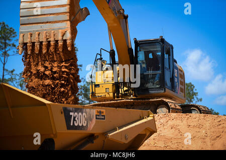 Sean Murry, opérateur d'équipement lourd avec le 796e Escadron de génie civil, dépôts de l'argile dans un rock-dump truck lors d'un projet de construction au camp James E. Rudder, en Floride, le 21 mars 2018. Ces aviateurs génie civil font partie d'une équipe qui gère l'équipement de construction lourde et détoner des explosifs dans le but de s'occuper et construire des installations. Banque D'Images