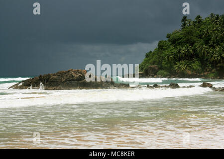 Plage de Mirissa, Sri Lanka : l'eau turquoise, du sable fin, des vagues pour le surf, parsemée de rochers et bordée de cocotiers. Le paradis ! Banque D'Images