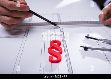 Close-up of Red paragraphe figure devant la main de l'architecte de travailler sur plan Banque D'Images