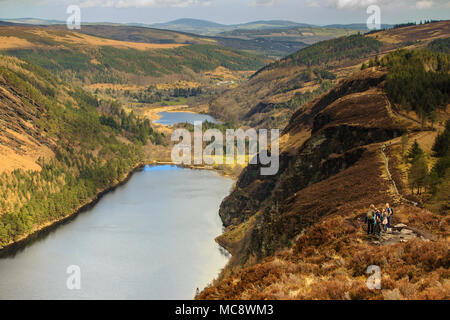 Groupe de randonneurs à la Spinc ridge admirant la vue spectaculaire de la vallée de Glendalough avec les lacs supérieur et inférieur et le site monastique dans l'arrière-plan. Banque D'Images