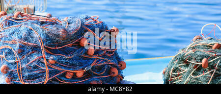 Des piles de filets de pêche sur le fond de l'eau de la mer bleue, la bannière. Port de Marsaxlokk, Malte Banque D'Images