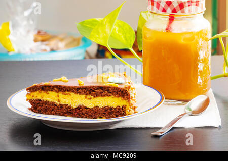 Délicieux gâteau au chocolat avec le verre de thé glacé ou de jus d'orange sur le tableau arrière-plan flou. Banque D'Images