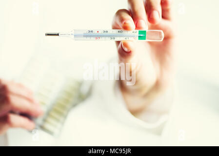 Tenir la main du médecin traditionnel classique pour mesurer la température du corps thermomètre et des pilules. Concept de la médecine. Copier l'espace. Banque D'Images