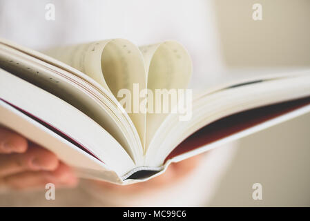 Livre avec pages ouvertes et la forme de coeur dans les mains de fille. Copier l'espace. Concept d'amour Banque D'Images