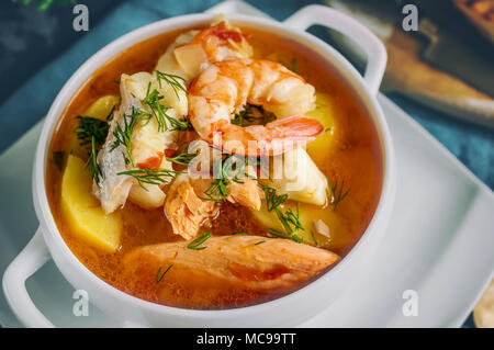 Soupe de poisson française Bouillabaisse aux fruits de mer, filet de saumon, crevettes, saveur riche, délicieux dîner dans un beau plat blanc. Close up. Banque D'Images