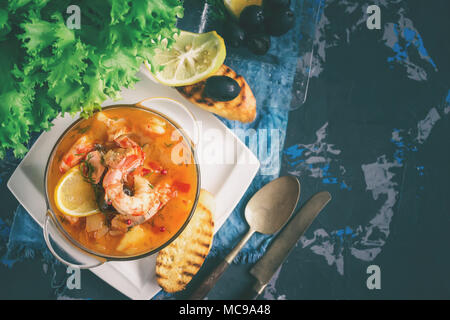 Soupe de poisson française Bouillabaisse aux fruits de mer, filet de saumon, crevettes, saveur riche, délicieux dîner dans un beau plat blanc. Close up. Spase copie Banque D'Images