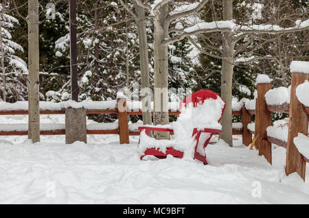 La neige a couvert une chaise rouge et la cour avant d'une cabine à Ashland, Oregon, United States. Banque D'Images