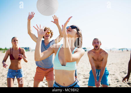 Groupe d'amis jouant au beach-volley sur la plage Banque D'Images