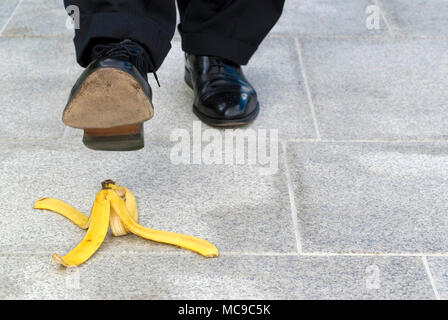 Businessman stepping sur peau de banane, copy space Banque D'Images