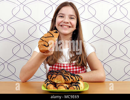 Happy little girl mange un croissant avec du chocolat Banque D'Images