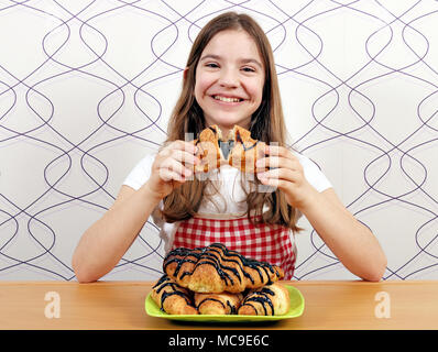 Happy little girl mange un croissant délicieux avec du chocolat Banque D'Images