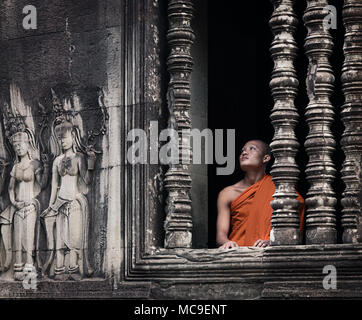 Siem Reap, Cambodge - janvier 19, 2011 : un moine dans sa robe orange est à la recherche du complexe d'Angkor Wat. Banque D'Images