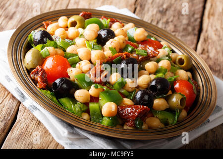 Salade de pois chiches est balela, tomates, oignons, olives et herbes gros plan sur une plaque horizontale, rustique. Banque D'Images