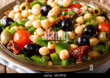 Salade de haricots du Moyen-Orient (Balela) avec les pois chiches, les tomates, les oignons, les olives et les herbes macro sur une assiette. L'horizontale Banque D'Images