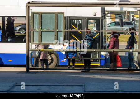 Riga, Lettonie, 11 avril 2018 : Les personnes en attente de l'autobus à l'arrêt de bus. Vue depuis l'arrière. Banque D'Images