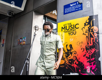 Musicien chanteur musicien ambulant Afro l'exécution devant une affiche disant Laissez la musique vous transporter à l'entrée de la station de métro de Brixton dans le Sud Banque D'Images