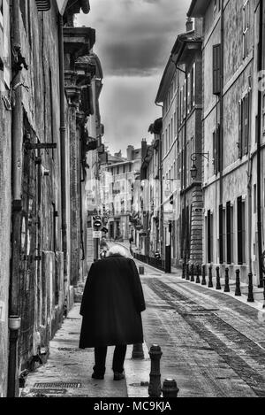 Noir et blanc photo verticale de dirigeant d'une personne sur une petite rue française, ni les bâtiments, ni la personne sont reconnaissables Banque D'Images