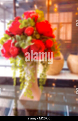 Image floue. rouge fleur dans un vase de l'arrière-plan du bureau. Banque D'Images