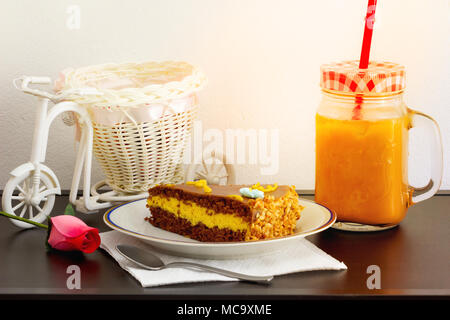 Soft focus. Délicieux gâteau au chocolat avec le verre de thé glacé ou de jus d'orange dans un café sur la table arrière-plan flou. Banque D'Images