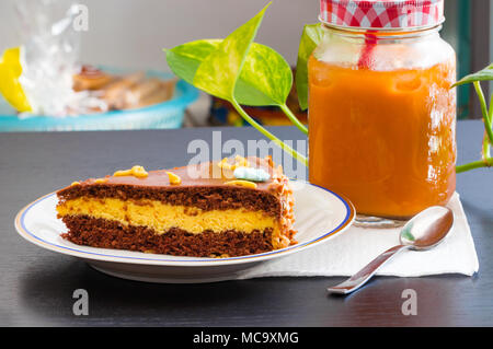 Délicieux gâteau au chocolat avec le verre de thé glacé ou de jus d'orange sur le tableau arrière-plan flou. Banque D'Images
