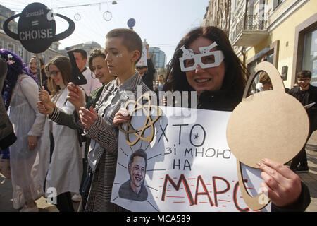 Kiev, Ukraine. 14 avr, 2018. Une femme porte une affiche avec une image de chef de la direction de SpaceX et Tesla Motors Inc. et Elon Musk lecture comme ''qui est avec moi sur Mars ?'', au cours de mars en costume-performance ''Marche pour la science'' dans le centre de Kiev, Ukraine, le 14 avril 2018. Vulgarisateurs de la science, les physiciens et les adeptes de la science ont pris part à l'action globale ''Marche pour la science'' pour la liberté de la recherche et de l'enseignement, au cours de la des rassemblements, qui ont eu lieu dans le monde le samedi. Crédit : Serg Glovny/ZUMA/Alamy Fil Live News Banque D'Images