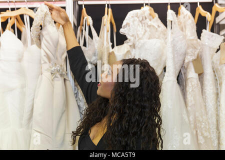 ExCel London, Londres, 14 avril 2018. Un jeune assistant s'occupe des belles robes sur l'affichage. Le mariage National spectacle a lieu au centre des expositions ExCel London ce week-end, mettant en valeur les dernières tendances, suite nuptiale, robes et accessoires tout autour de la planification du mariage parfait. Credit : Imageplotter News et Sports/Alamy Live News Banque D'Images