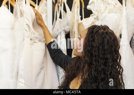ExCel London, Londres, 14 avril 2018. Un jeune assistant s'occupe des belles robes sur l'affichage. Le mariage National spectacle a lieu au centre des expositions ExCel London ce week-end, mettant en valeur les dernières tendances, suite nuptiale, robes et accessoires tout autour de la planification du mariage parfait. Credit : Imageplotter News et Sports/Alamy Live News Banque D'Images